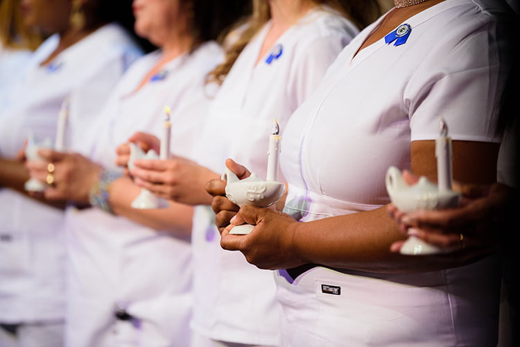Falcon Institute nursing graduates ceremony showing healthcare professionals with candles during pinning tradition
